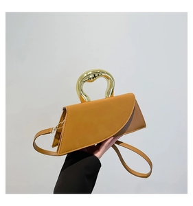 Detail of caramel geometric handbag with oversized gold metal handle and strap