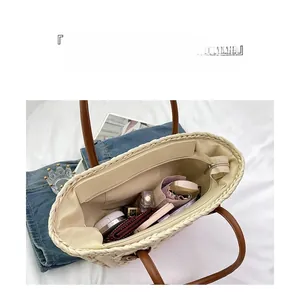 Internal view of straw tote bag with brown leather handles and functional compartments