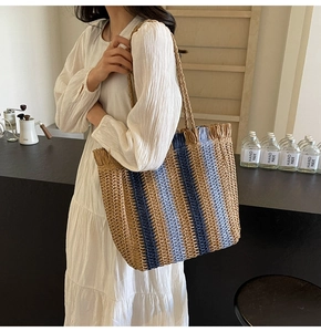 Close-up of woven straw tote bag featuring blue stripes and delicate fringe detail