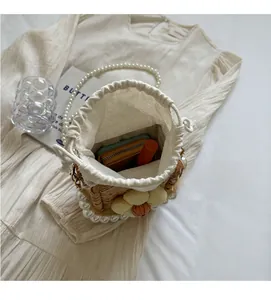 Internal view of straw bucket bag with large pearls handle and floral detail