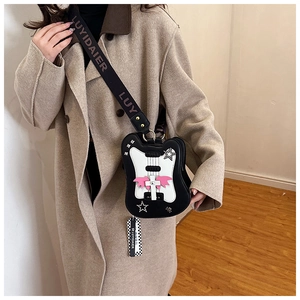 Guitar-shaped crossbody bag with pink wings and star studs worn by a model in a coat