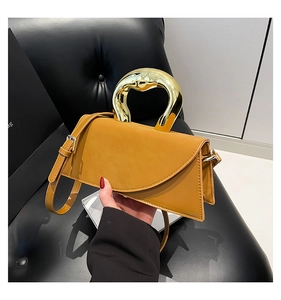 Detail of yellow geometric handbag featuring unique gold metal handle and matte leather finish