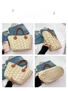 Detail view of woven straw tote bag with brown leather handles and textured stitching
