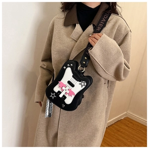 Detailed shot of guitar-shaped crossbody bag with pink wings and brand strap on a model