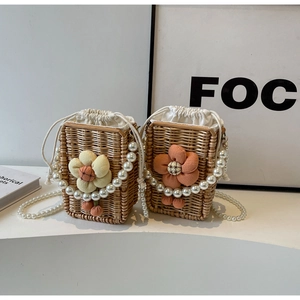 Detail of hand-woven straw crossbody bag with floral accents and pearl chain strap