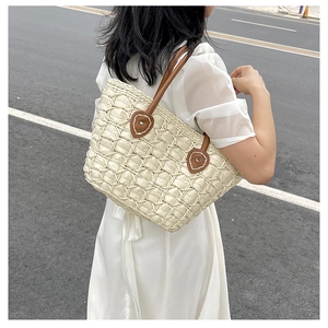 Detail of hand-woven beige straw tote bag with brown leather handles and stitching