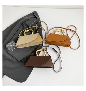 Detailed view of fashionable trapezoid handbags with unique gold metal handles in three colors