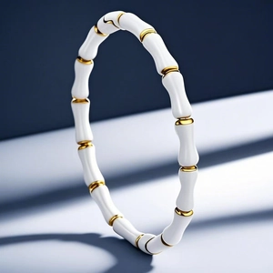 Detalle de una pulsera de bambú con secciones de esmalte blanco y anillos dorados