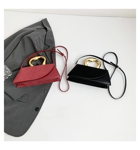 Detail of elegant small square handbags with gold heart-shaped handles on a grey blazer