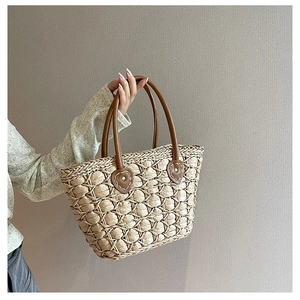 Detail of hand-woven straw tote with leather handles and heart-shaped decorative patches