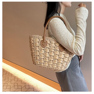 Close-up of khaki straw woven tote bag with brown leather handles and textured honeycomb weave