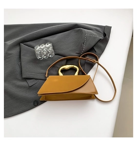 Close-up of caramel leather handbag featuring a unique gold irregular metal handle