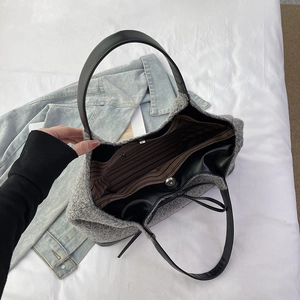 Large gray knitted tote bag with brown striped lining and black leather handles