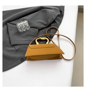 Detail of mustard yellow geometric bag with artistic gold handle and matte leather texture