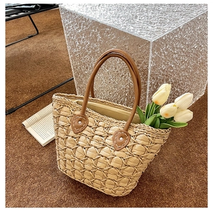 Close-up of woven straw handbag texture with brown leather handles and tulips