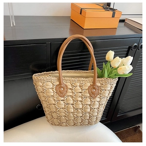 Detail of woven straw tote with brown leather heart-shaped handle reinforcements
