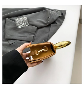 Detail view of brown leather bag showing gold curved handle and accordion side design