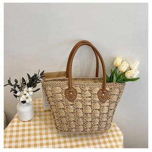 Detail of handwoven straw tote featuring leather handles and secure metal rivets