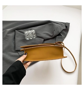 Detail view of the caramel leather bag's gusseted bottom and adjustable shoulder strap