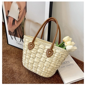Detailed view of natural straw mesh texture and brown leather handles on a tote bag