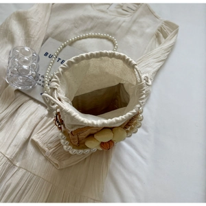 Detailed view of handmade woven straw bag with floral decor and pearl beaded handle