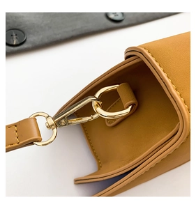 Detailed macro view of the golden lobster clasp and stitching on a yellow leather handbag