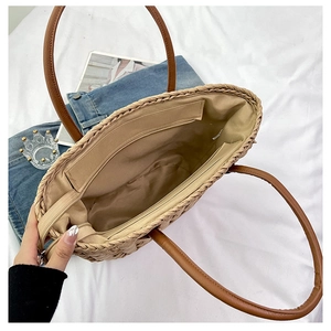 Straw tote bag interior showing textile lining zipper pocket and brown leather handles