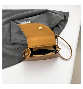 Detail view of ginger yellow saddle bag interior with zipper pocket and magnetic clasp