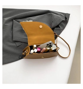 Detail view of compact saddle bag interior holding a smartphone and lipsticks