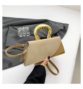 Detail of elegant two-tone beige and brown square handbag with gold streamlined handle