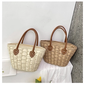 Detail of woven straw bag with square texture, leather handles and heart leather patch