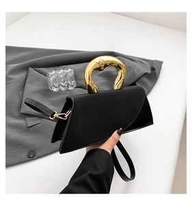 Detail of artistic gold irregular geometric handle on minimalist black leather handbag