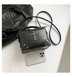 Detail of Y2K gothic crossbody bag with silver cross, chain, and metal rivet corners