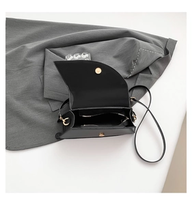 Interior view of black leather saddle bag with gold magnetic clasp and inner zip pocket