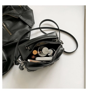 Top view of black crossbody bag with silver zipper showing interior for cosmetics