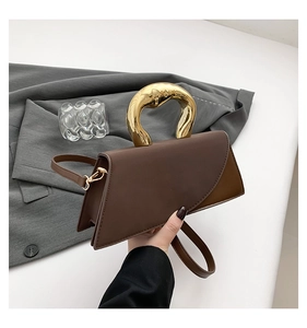 Detail of artistic gold irregular handle on a brown leather geometric tote bag