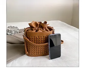 Brown woven bucket bag size comparison with a smartphone showing textured leather detail