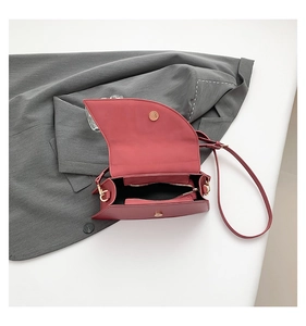 Detail view of brick red saddle bag interior with magnetic clasp and golden hardware