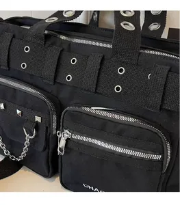 Détail d'un sac en toile noire avec fermetures éclair, chaînes et œillets argentés