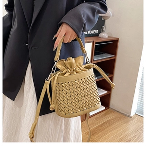 Close-up of woven bucket bag featuring drawstring closure and adjustable crossbody strap
