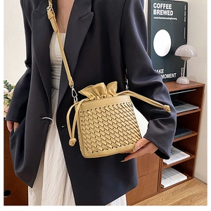 Detail showing cream woven bucket bag with drawstring closure and frill trim design