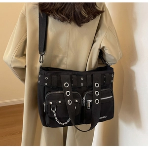 Détail du sac punk en toile avec rivets argentés et chaînes sur un manteau beige
