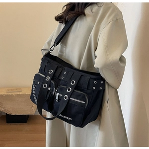 Gros plan sur le sac messager punk en toile noire avec rivets et détails de chaîne