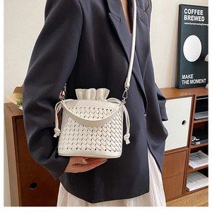 Detail of white woven bucket bag showing intricate cutout leather texture and drawstring liner