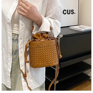 Woven brown bucket bag styled with a drawstring pouch and slim shoulder strap