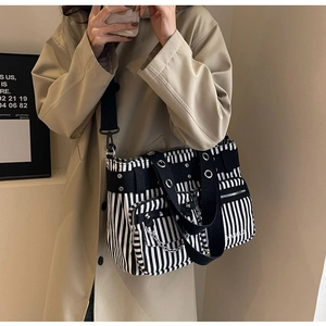 Détail du sac en toile avec rivets punk, chaînes argentées et rayures noires et blanches
