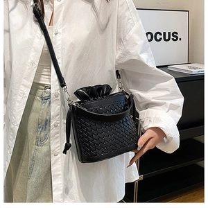 Detail of black woven crossbody bucket bag featuring elegant drawstring silk lining