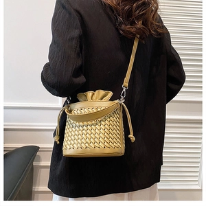 Detail of light yellow woven bucket bag with drawstring closure and crossbody strap