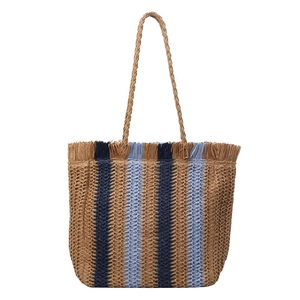 Large woven straw tote bag with blue stripes, fringe trim and dual handles on white background