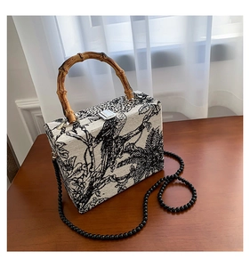 Detail of vintage floral embroidery on the bag with a natural bamboo top handle